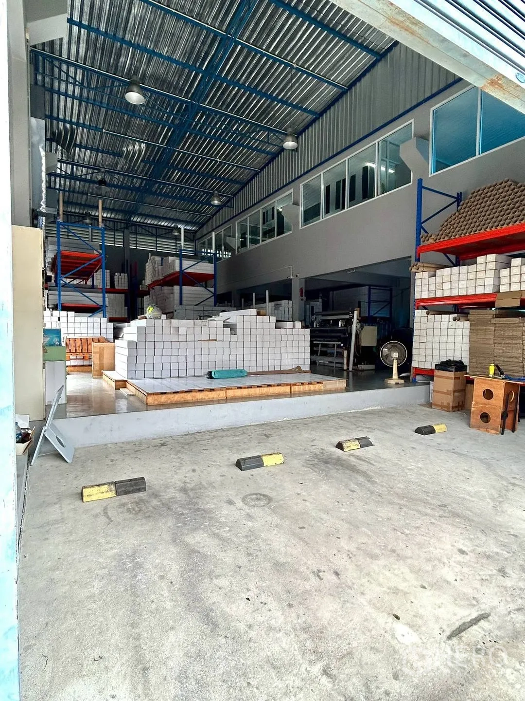 Warehouse for rent in Suan Luang, Bangkok - Loading area with storage racks and stacked goods under a high metal roof.