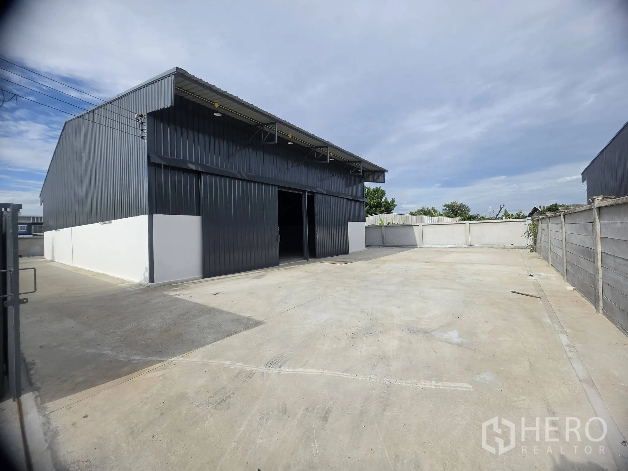 Warehouse for rent in Mueang Samut Prakan, Samut Prakan - Spacious loading and parking yard in front of a warehouse within a walled compound.