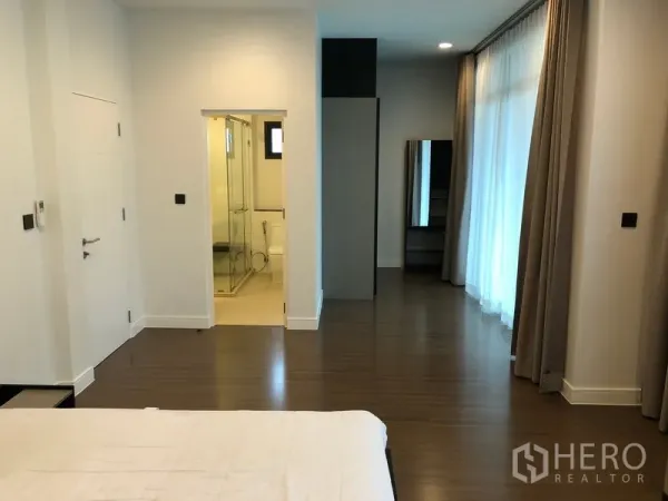 Detached House for rent or sale in Bang Kapi, Bangkok - Spacious master bedroom with floor-to-ceiling windows, wardrobe and ensuite bathroom with glass shower.
