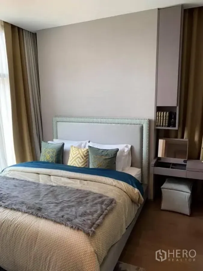 Condominium for rent in Bang Rak, Bangkok - Master bedroom of a Bang Rak condo with upholstered headboard, study nook, and floor-to-ceiling window.