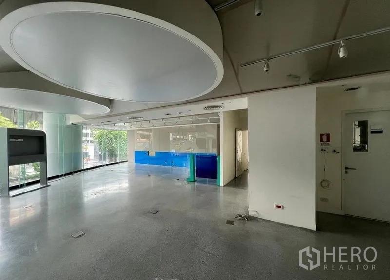 Retail Space for rent - Open-plan retail interior with floor-to-ceiling windows, track lighting and polished concrete floor.
