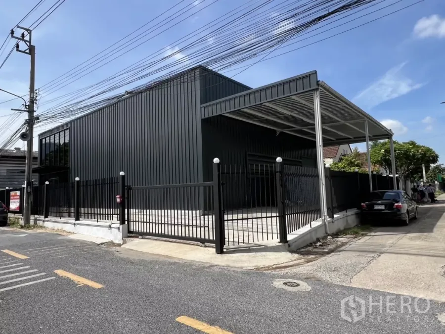 货栈 出租在Bang Na, Bangkok - 仓库正立面，滑动栅栏门、雨棚及车道停车位。
