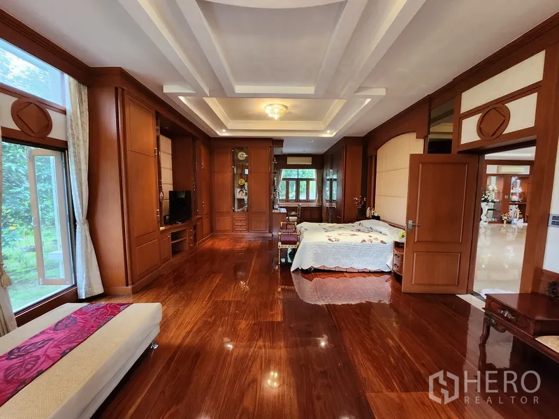 Detached House for rent in Prawet, Bangkok - Master suite with extensive built‑in wood cabinetry, garden views and coffered ceiling.