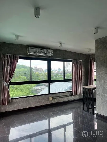 联排别墅 出租在Phaya Thai, Bangkok - 高层房间，宽幅窗户可见树梢与城市景色，灰色亮面地砖。