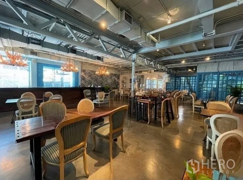 Retail Space for rent in Watthana, Bangkok - Spacious restaurant-style interior with exposed ceiling, bar, and mixed wooden tables and chairs.