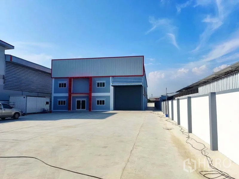 Factory for sale in Mueang Samut Sakhon, Samut Sakhon - Wide driveway leading to factory building, surrounded by high boundary walls.