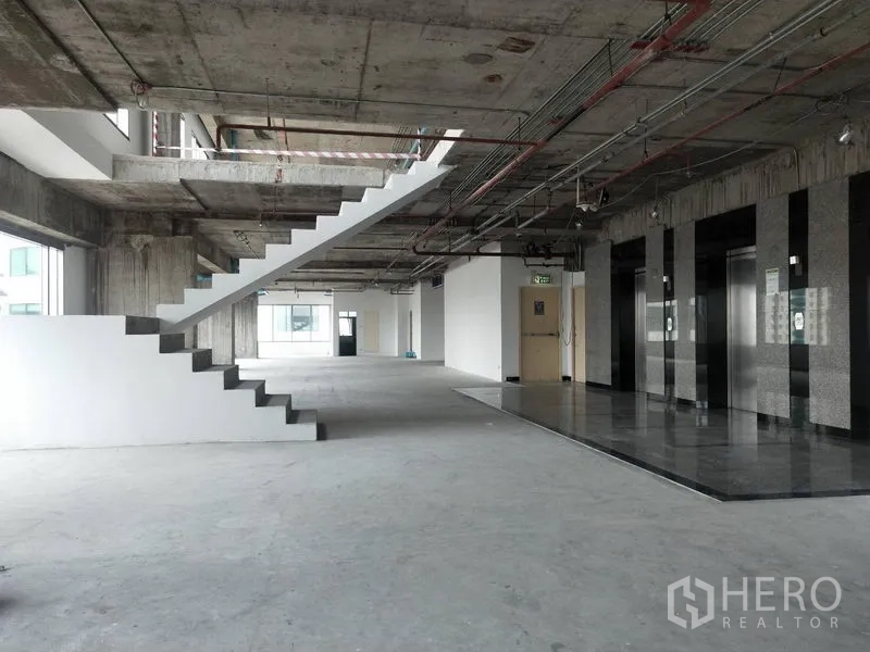 Office Space for rent in Watthana, Bangkok - Unfinished office lobby featuring elevators and an internal staircase.
