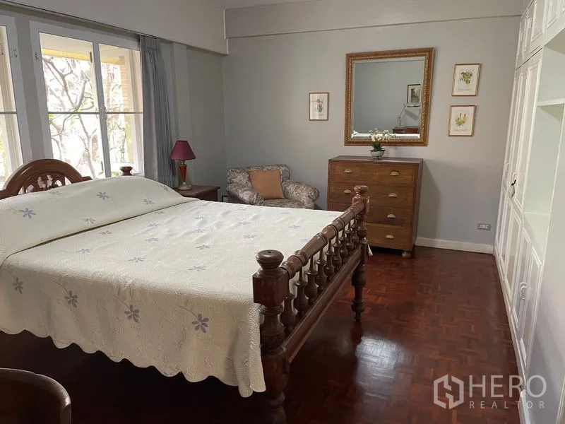 Condominium for rent in Watthana, Bangkok - Bedroom with classic wooden bedframe, dresser and seating corner.