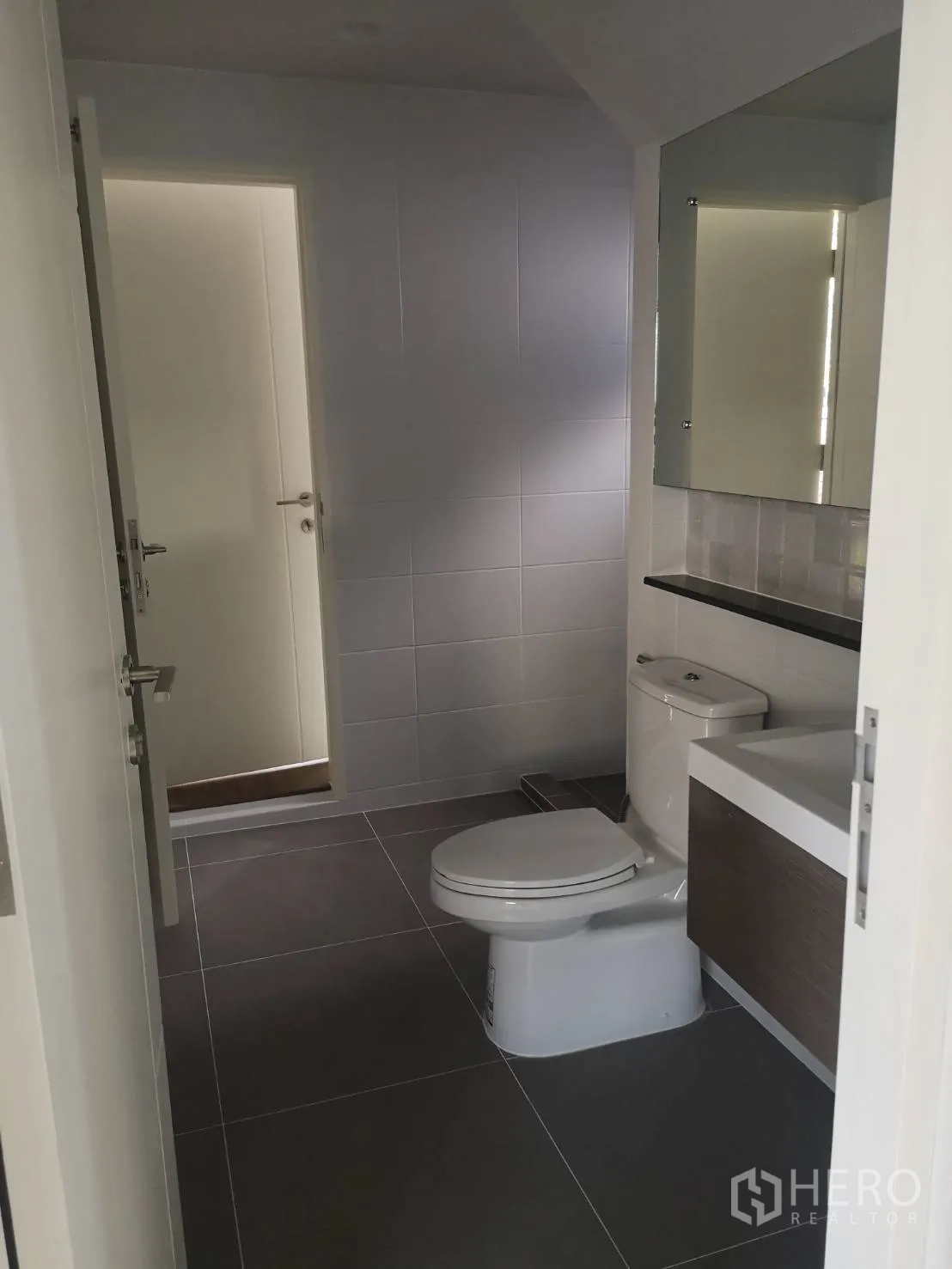Detached House for sale in Lam Luk Ka, Pathum Thani - Downstairs restroom with toilet, vanity and a large mirror.