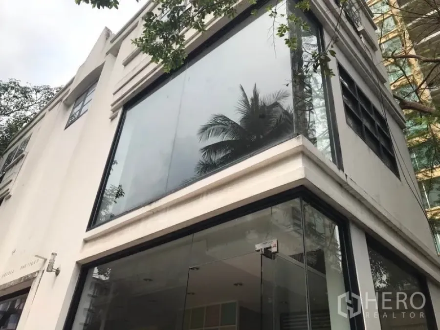 Retail Space for rent in Watthana, Bangkok - Corner two-storey retail exterior in white with large glass facade and tree reflections.