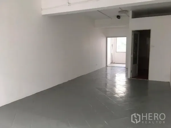 Shophouse for rent in Khlong Toei, Bangkok - Upper-floor area with gray tiled floor, white walls, and a doorway leading to a small balcony space.