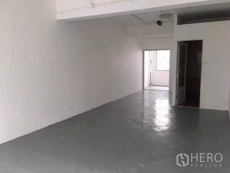 Shophouse for rent in Khlong Toei, Bangkok - Upper-floor area with gray tiled floor, white walls, and a doorway leading to a small balcony space.