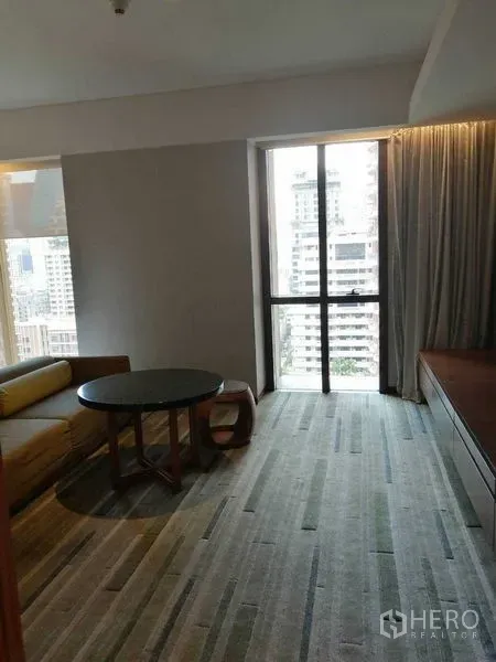 Condominium for rent in Pathum Wan, Bangkok - City-view window bringing natural light into the lounge with sofa and coffee table.
