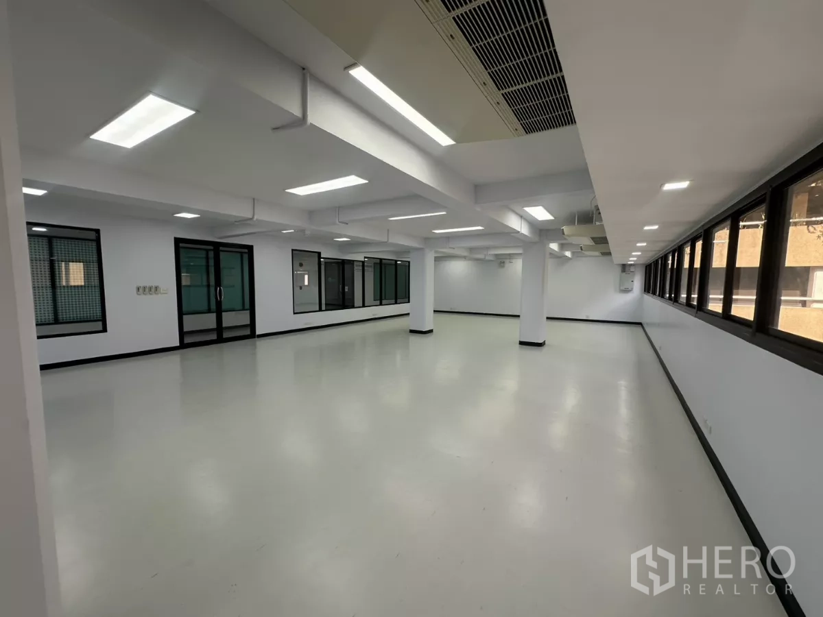 Office Space for rent - Spacious workspace featuring a row of windows, recessed panel lighting and a glass door entry.