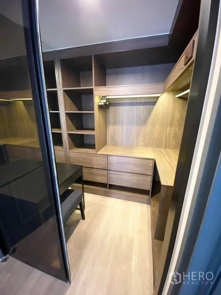 Condominium for rent in Pathum Wan, Bangkok - Walk-in closet with built-in wooden shelves, drawers and a small desk.