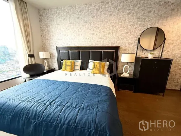Condominium for rent - Bright bedroom with padded headboard, blue duvet and large city-view window.