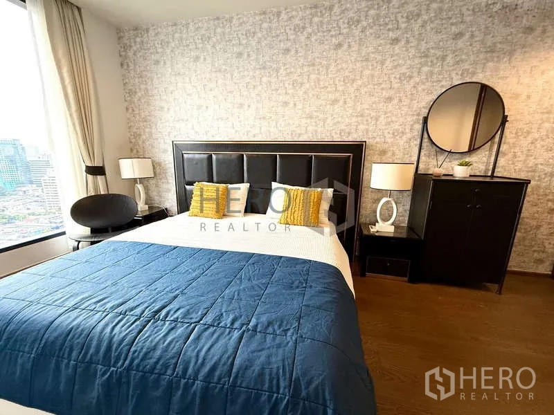 Condominium for rent - Bright bedroom with padded headboard, blue duvet and large city-view window.