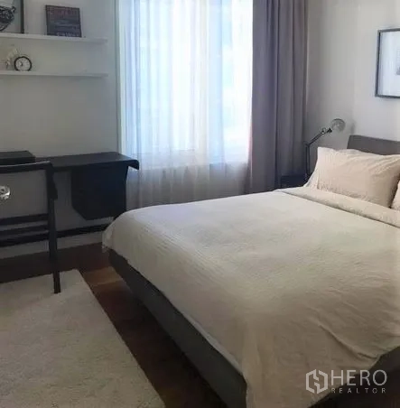 Condominium for rent in Pathum Wan, Bangkok - Second bedroom with double bed, study desk, wall shelves and a large window.