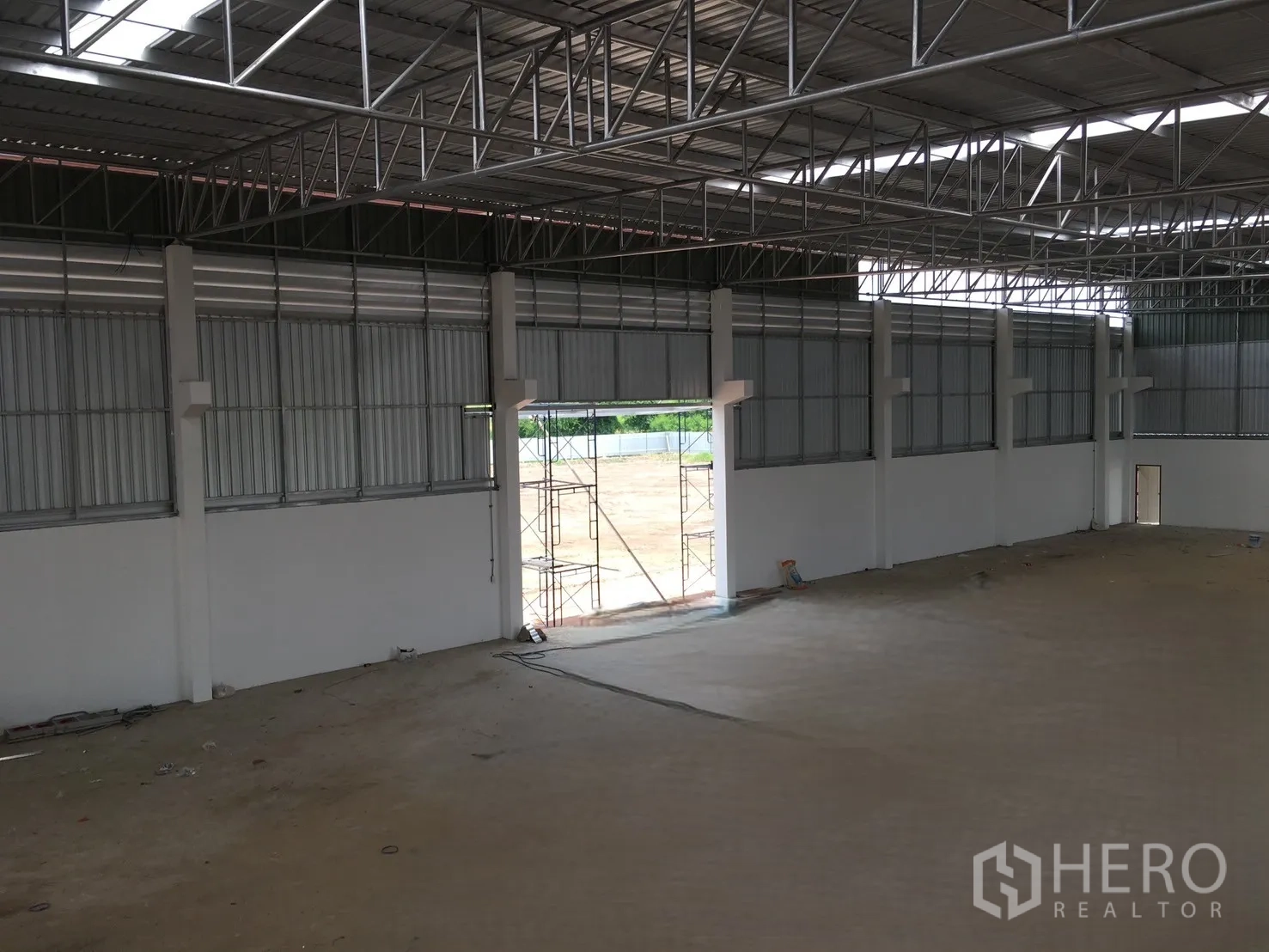 Warehouse for sale in Sai Noi, Nonthaburi - Interior view of a high-clearance storage hall with ventilation panels and a large access opening to the yard.