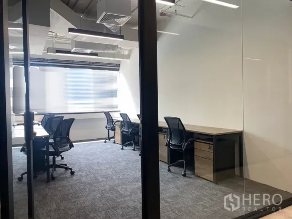 Office Space for rent in Bang Rak, Bangkok - Glass-partitioned workspace with rows of desks, carpet flooring and under-desk pedestals.