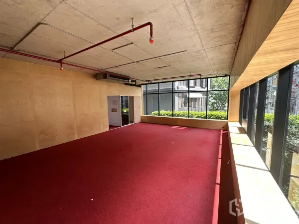 Retail Space for rent in Watthana, Bangkok - Upper floor open-plan area with red carpet, plywood walls and floor-to-ceiling windows.