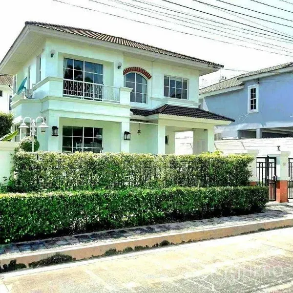 Detached House for rent in Prawet, Bangkok - Two-storey detached house with white facade, balcony and trimmed hedge in a gated community.