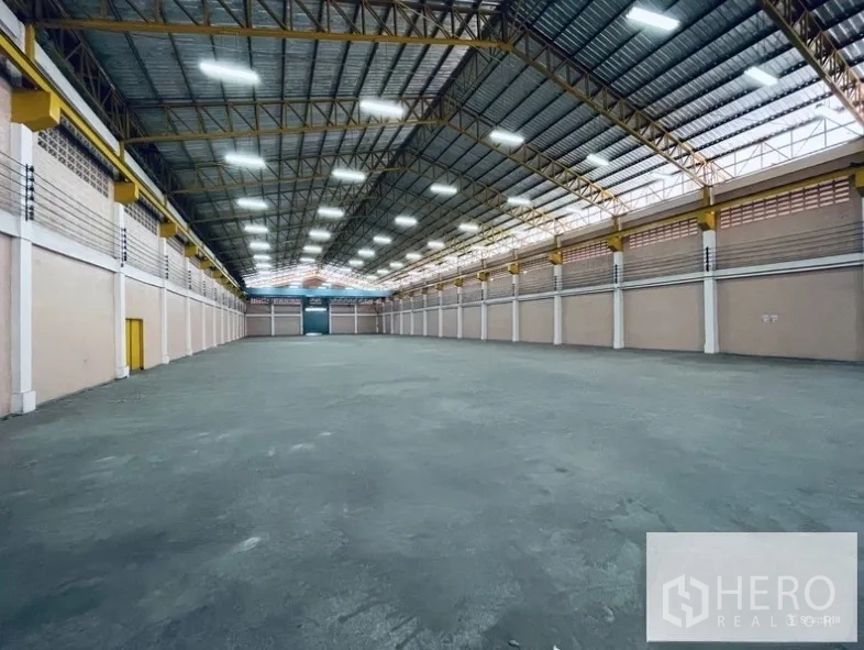 Warehouse for rent in Sam Phran, Nakhon Pathom - Expansive clear-span warehouse floor under a steel truss roof with bright high-bay lighting.