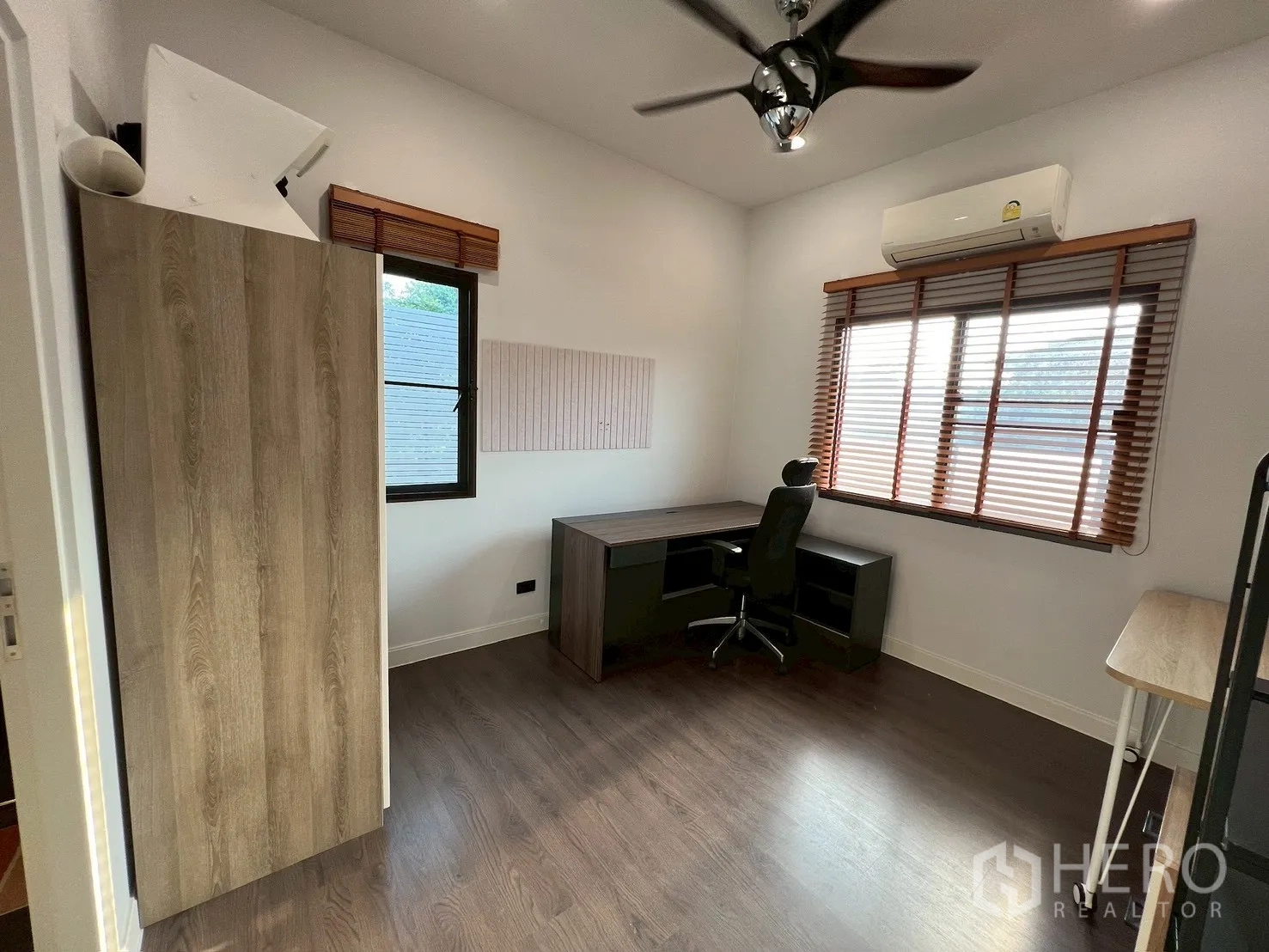 Detached House for rent in Bang Kapi, Bangkok - Bright home office with L-shaped desk, wood floors, ceiling fan and window blinds.