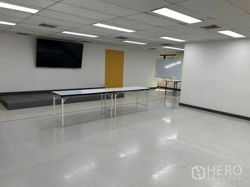 Office Space for rent in Khlong Toei, Bangkok - Large training-style office room with wall-mounted screen, small stage, and ceiling grid lights.