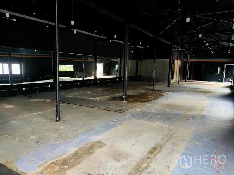 货栈 出租在Suan Luang, Bangkok - 高挑仓库内部，钢柱支撑，墙面镜面装饰与混凝土地面。