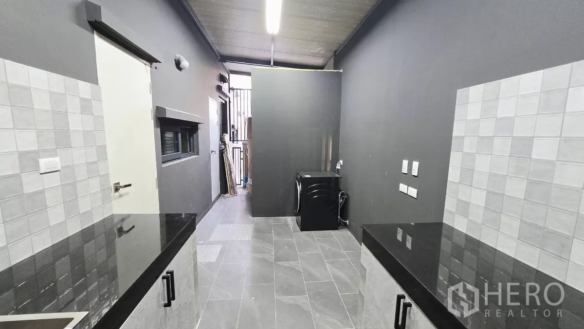 Detached House for rent in Prawet, Bangkok - Service zone with Thai kitchen and laundry area on grey tile flooring.