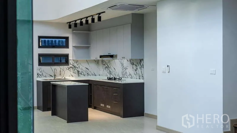 Detached House for rent or sale in Suan Luang, Bangkok - Built-in kitchen with island, marble backsplash and gas cooktop under track lights