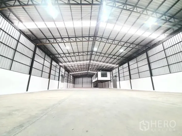 Warehouse for rent in Bang Khen, Bangkok - Wide-angle view of the high-bay warehouse showing smooth concrete floor and metal panel walls.