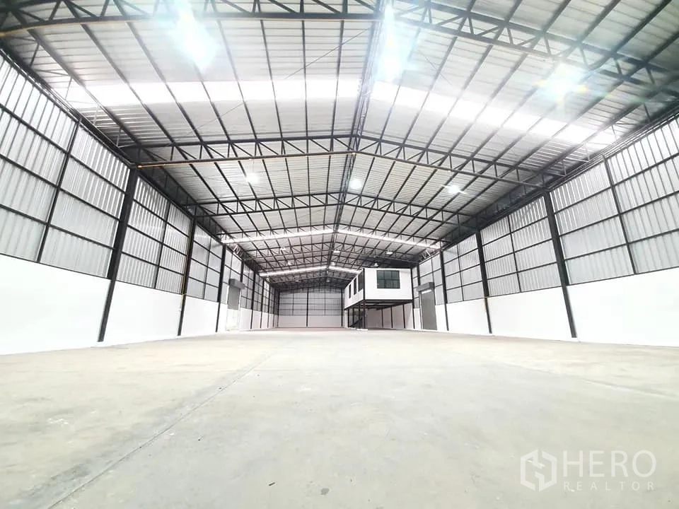 Warehouse for rent in Bang Khen, Bangkok - Wide-angle view of the high-bay warehouse showing smooth concrete floor and metal panel walls.