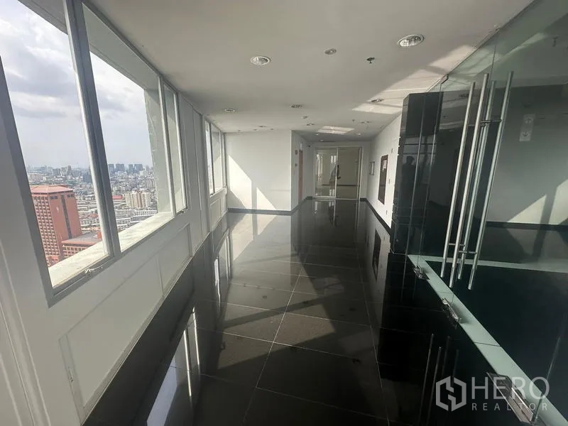 Office Space for rent - High-floor corridor and lobby with glossy black tiles, glass entry, and continuous city-facing windows.
