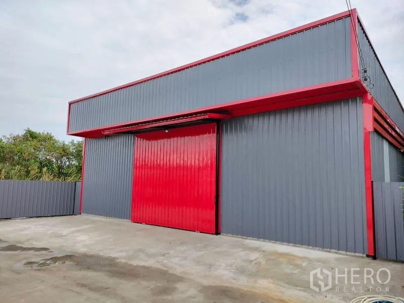 Warehouse for rent in Bueng Kum, Bangkok - Modern grey warehouse with a large red sliding door and spacious concrete loading area in Bueng Kum, Bangkok.