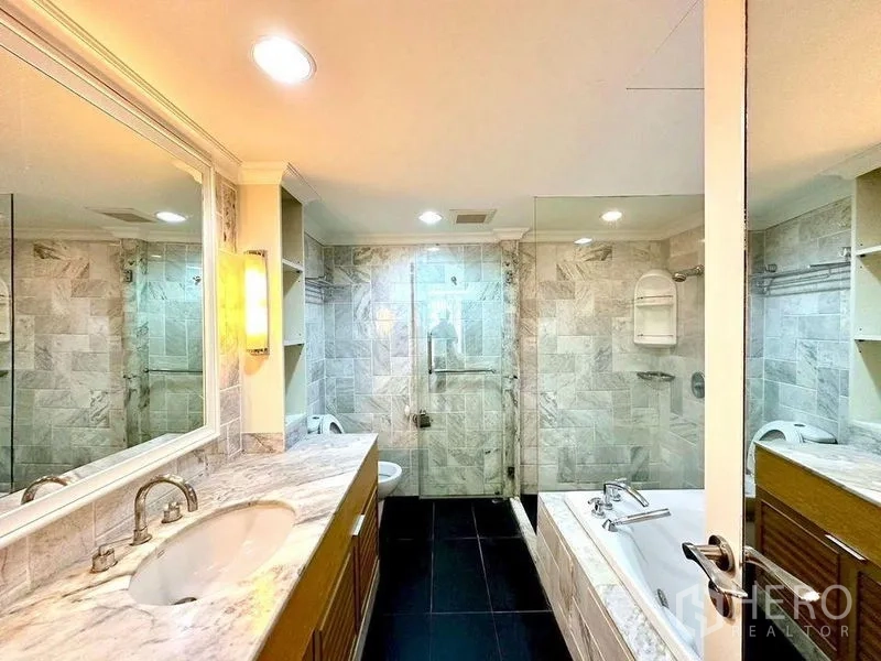 Condominium for rent - Vanity area with marble countertop, large mirror and walk-in glass shower next to tub.