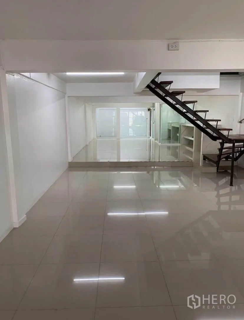 Townhouse for rent in Phra Khanong, Bangkok - Bright open-plan living area with glossy tile floors and a modern staircase.