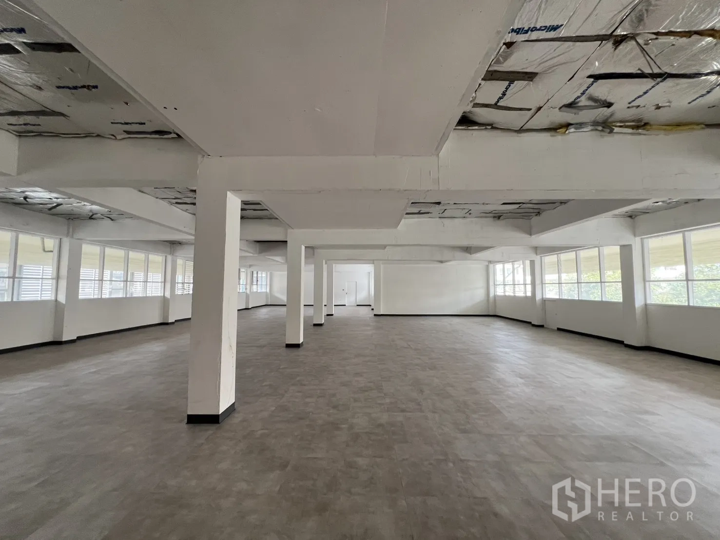 Office Space for rent in Watthana, Bangkok - Expansive columned workspace with multiple windows and durable vinyl flooring.
