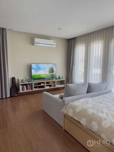 Detached House for rent or sale in Bang Khen, Bangkok - Alternate view of the master bedroom with TV console, curtains and wood flooring.