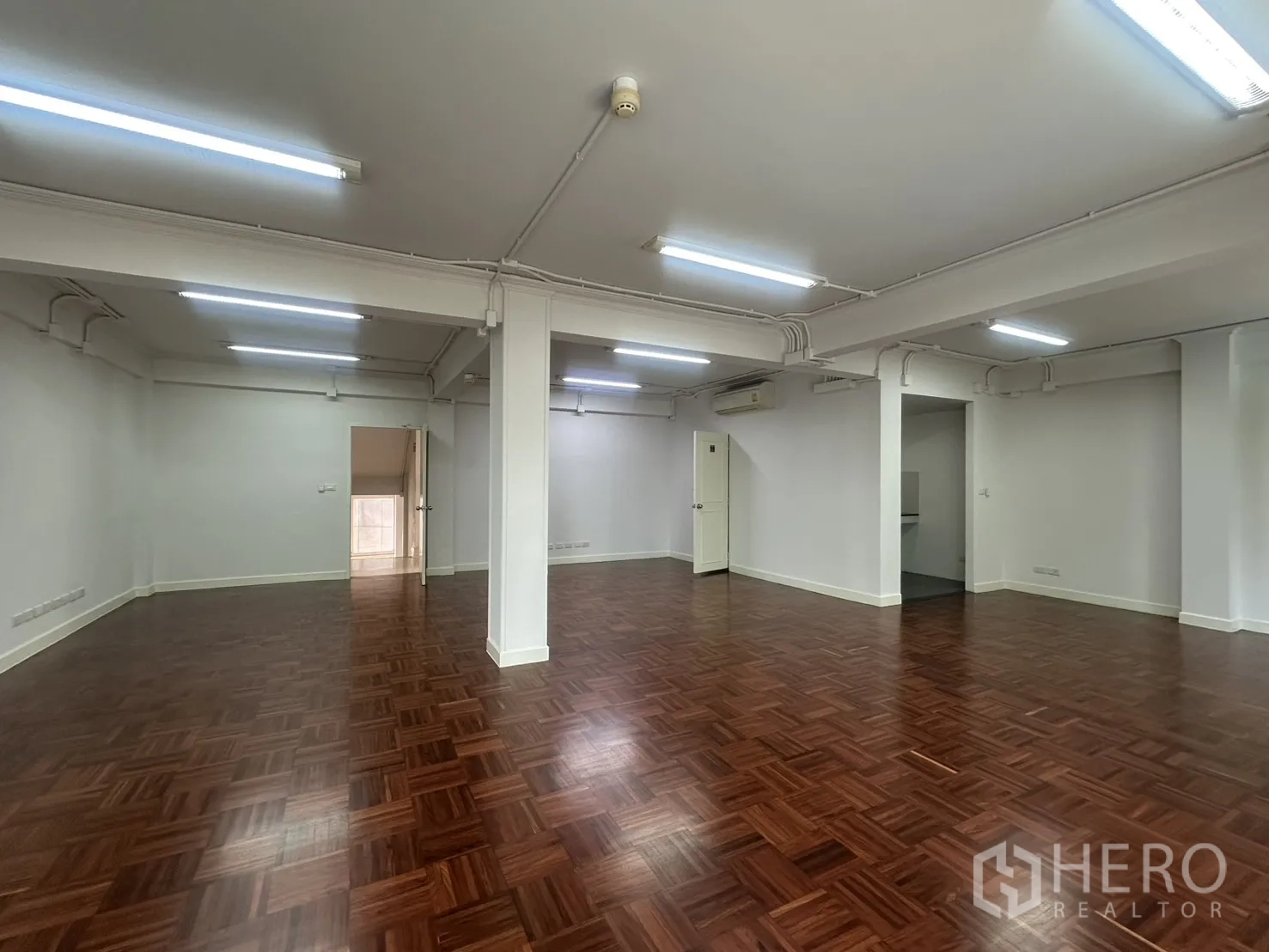 Office Space for rent in Watthana, Bangkok - Bright open workspace with columns, strip lighting, and glossy wooden floors.