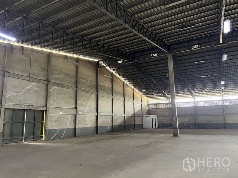 Warehouse for rent - Warehouse corner with high concrete walls, side door and small utility room.