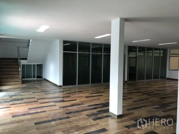 工厂 出租在Samut Prakan - 开放式办公区，木纹地板、玻璃隔间与通往二层的楼梯。