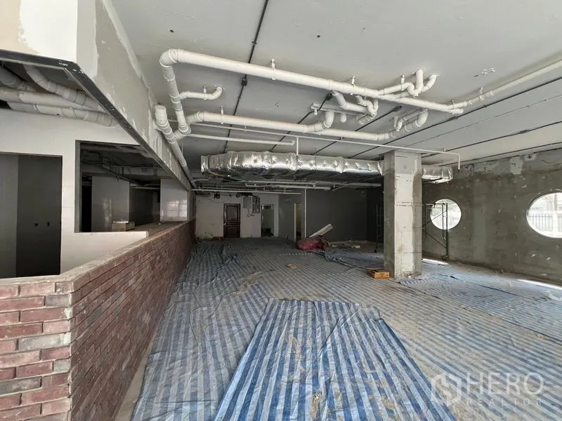 Retail Space for rent in Watthana, Bangkok - Open-plan floor with exposed ducting, brick half wall, and round windows.