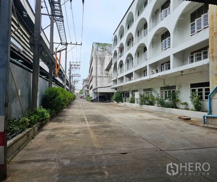 Factory for rent in Bang Kho Laem, Bangkok - Private access road lined with buildings, greenery and power lines.