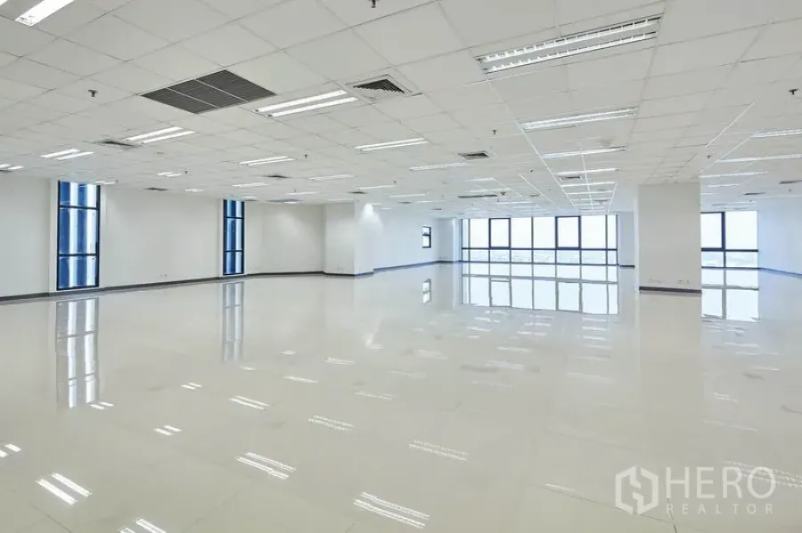 Office Space for rent in Bang Na, Bangkok - Bright open-plan office with grid ceiling, LED lights, polished tile floors and large blue-framed windows.