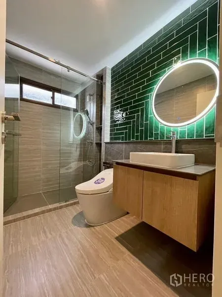 Detached House for sale in Bang Kapi, Bangkok - Contemporary bathroom featuring glass shower, green subway-tile wall, backlit round mirror and floating vanity.