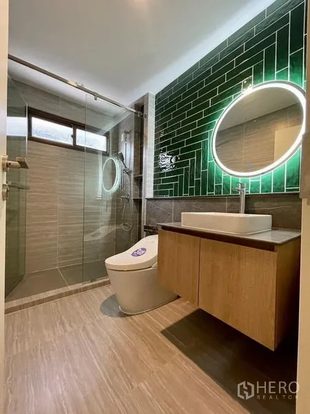 Detached House for sale in Bang Kapi, Bangkok - Contemporary bathroom featuring glass shower, green subway-tile wall, backlit round mirror and floating vanity.