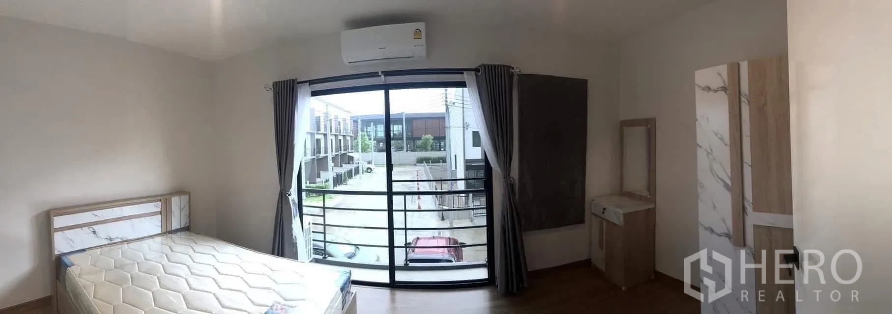 Townhouse for rent or sale in Prawet, Bangkok - Bedroom with sliding doors opening to a balcony overlooking the townhouse street.
