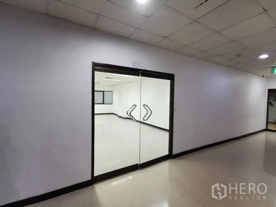Office Space for rent in Watthana, Bangkok - Building corridor view of the unit’s clear glass double-door entrance.